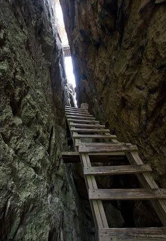 Looking up a ladder between two rock walls